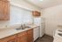 Bright kitchen with modern appliances, wooden cabinets, and ample natural light from a large window with blinds.