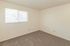 Bright and cozy room featuring plush carpet flooring and a wide window with blinds, perfect for a relaxing bedroom or office space.