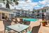 Inviting apartment complex featuring a sparkling outdoor pool surrounded by modern lounge chairs, perfect for relaxation under a clear blue sky.