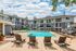 Charming apartment complex with a sparkling outdoor pool surrounded by modern lounge chairs and greenery, offering a relaxing community atmosphere.