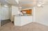 Inviting open-concept apartment with a cozy living area, modern ceiling fan, and a sleek kitchen featuring warm wooden cabinets and white appliances.