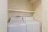 Compact laundry nook with modern washer and dryer, featuring convenient overhead shelving.