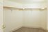 Spacious walk-in closet with ample shelving and neutral carpet flooring, perfect for organizing your wardrobe.