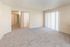 Bright, spacious living area with plush carpeting and large sliding glass doors for natural light.