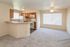 Bright and inviting living space featuring an open-plan kitchen with modern appliances, cozy carpeted area, and ample natural light.
