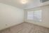 Bright and airy empty room with plush carpeting and a large window, ready to be transformed into your dream space.