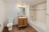 Bright and modern bathroom with elegant fixtures, featuring a large mirror, sleek vanity, and spacious bathtub with contemporary tilework.