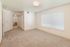 Bright and spacious bedroom featuring soft carpet flooring, expansive windows with blinds, and a convenient en-suite bathroom access.