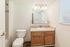 Bright, modern bathroom with elegant wooden cabinetry, pristine countertop, and ample natural light from a large window.