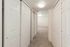 Bright and airy hallway featuring sleek white sliding closet doors and plush carpet flooring, leading to a spacious living area.