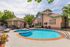 Inviting apartment pool area with lush greenery, cozy loungers, and charming architecture, perfect for relaxation.