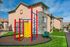 Inviting apartment complex with vibrant playground and lush green surroundings, perfect for family living and outdoor enjoyment.