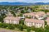Charming aerial view of a serene apartment complex surrounded by lush greenery and picturesque mountains, offering idyllic living and scenic landscapes.