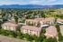 Aerial view of charming apartment complex nestled in a lush suburban neighborhood with scenic mountain backdrop, ideal for serene living.