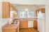 Bright and inviting kitchen with wooden cabinetry, ample counter space, modern appliances, and natural light from dual windows.