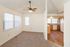 Bright and inviting apartment featuring a cozy living area with plush carpeting, modern ceiling fan, and a well-lit kitchen accented with wooden cabinetry and spacious countertops.