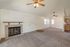Inviting living room with vaulted ceiling, cozy fireplace, and ceiling fans, seamlessly leading to a charming kitchen area.