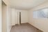 Inviting bedroom with plush carpeting, freshly painted walls, and ample natural light through vertical blinds.