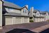 Charming multi-unit townhouse with private garages and modern architectural design, set against a clear blue sky.