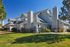 Charming suburban home with modern architecture, lush green lawn, and vibrant blue sky backdrop.