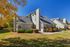 Charming townhouse with elegant architecture, surrounded by lush greenery and autumn foliage, under a clear blue sky.