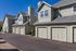 Charming townhouse exterior with classic green siding, multiple garages, and sunny blue skies offering a welcoming curb appeal.
