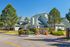Charming suburban apartment complex with lush greenery and modern architecture under a clear blue sky.