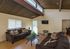 Inviting living room with rich wooden ceiling, cozy couches, and stylish decor, featuring large windows for ample natural light.