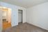Inviting bedroom with plush carpeting, ample closet space, and a view into a bright hallway with sleek hardwood floors.