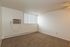 Bright and cozy room with soft carpeting, featuring a wall-mounted air conditioner and large window letting in natural light.