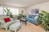 Charming living room with elegant blue sofas, lush indoor plants, and a cozy ambiance perfect for relaxation.