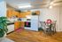 Charming kitchen and dining area featuring warm wooden cabinets, a spacious countertop, modern appliances, and a cozy dining nook with a glass table and stylish chairs, perfect for any home cook.