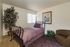 Cozy bedroom adorned with a charming bed in soft lavender tones, framed artwork, and vibrant potted plant, exuding warmth and comfort.
