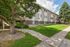 Charming apartment building surrounded by lush greenery and a well-maintained lawn, perfect for tranquil living.
