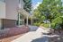 Charming apartment entrance with a scenic walkway lined with vibrant flowers and lush greenery, providing a welcoming and tranquil atmosphere.