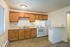 Charming kitchen with warm wooden cabinetry, modern appliances, and sleek countertops offering a cozy and functional cooking space.