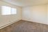 Bright, spacious bedroom with plush carpeting and large window, perfect for a cozy and inviting living space.