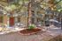 Charming apartment complex with a rustic exterior, surrounded by lush trees and featuring a cozy courtyard with a vibrant flower bed and a shaded seating area.