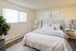 Bright and inviting bedroom with modern decor, featuring a plush bed, elegant lamps, and a large window for natural light.