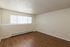 Bright and inviting room with elegant wood flooring, featuring ample natural light through modern vertical blinds, perfect for a cozy living space.