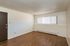 Inviting room with elegant wood flooring, a modern light fixture, and a large window providing ample natural light.