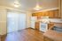 Bright kitchen with modern appliances, warm wooden cabinetry, and elegant laminate flooring, featuring large patio doors for natural light.