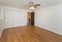 Inviting room with modern wooden flooring, bright white walls, and a ceiling fan, perfect for a cozy living space or home office.
