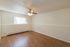 Bright and airy room with elegant wooden flooring, modern ceiling fan, and large window offering ample natural light.