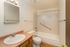 Modern bathroom with elegant fixtures, featuring a sleek vanity, bathtub with safety rail, and contemporary lighting.