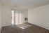 Bright and airy room featuring plush carpet, sliding glass door with vertical blinds, and wall-mounted air conditioning unit, perfect for comfortable living.