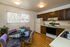 Charming kitchen with wooden cabinetry, cozy dining area with stylish chairs, and abundant natural light from a large window.