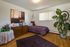Charming bedroom with stylish decor featuring a cozy bed dressed in lavender, elegant wooden dresser, vibrant art piece, and lush indoor plant.