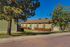 Charming green apartment complex surrounded by trees and a well-maintained lawn, offering a serene living environment with a clear blue sky overhead.