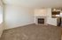 Inviting living area with cozy carpet flooring, elegant corner fireplace, and view into a charming kitchen.